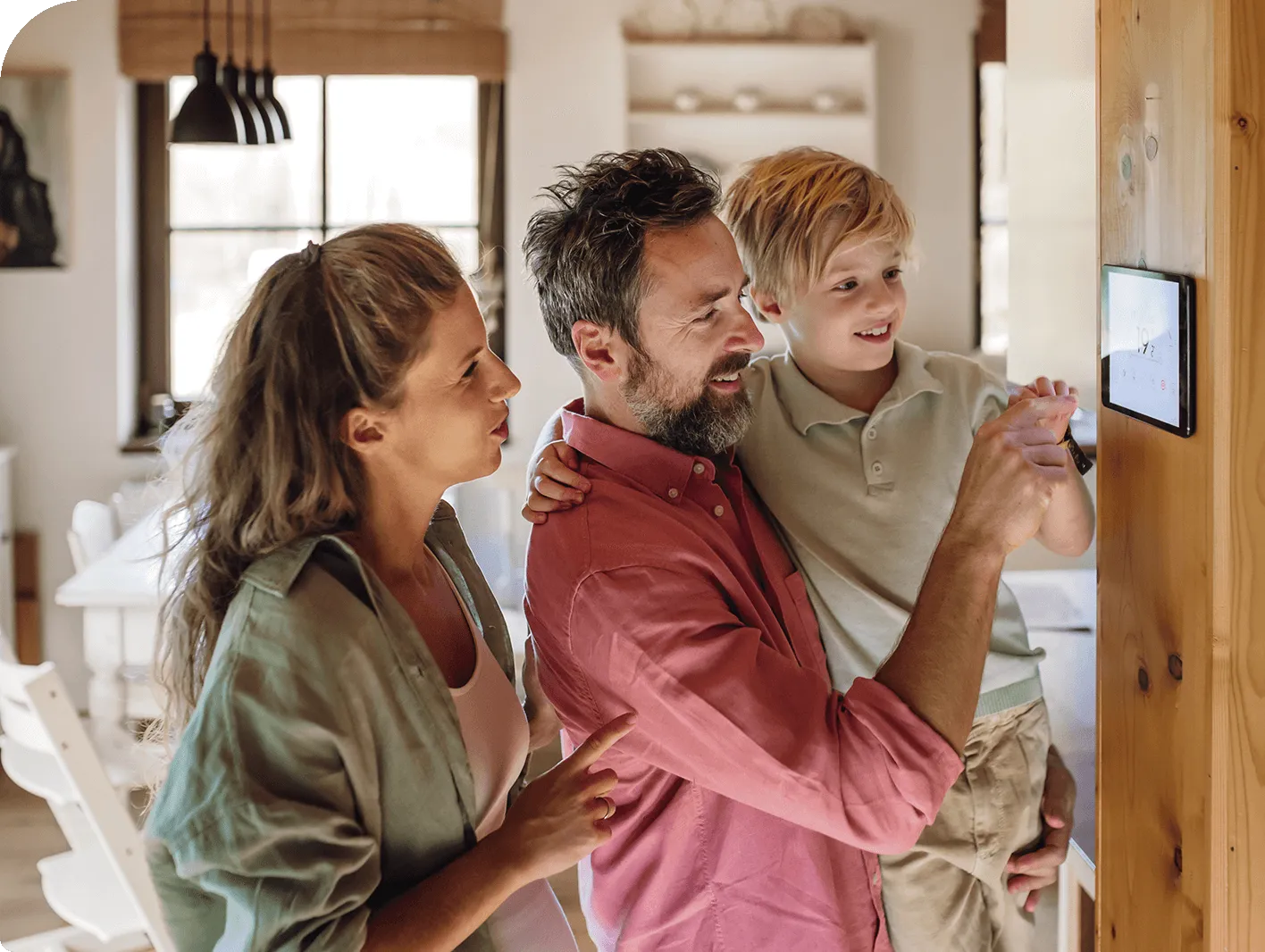 A smiling family adjusting a smart home thermostat on the wall together.