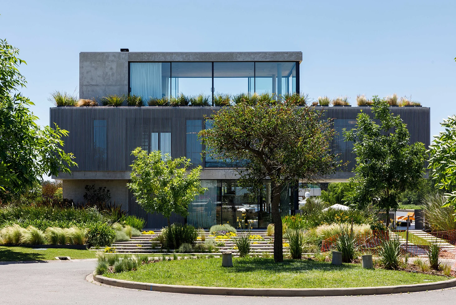 Nordelta residential modern home facade with trees and landscaping.
