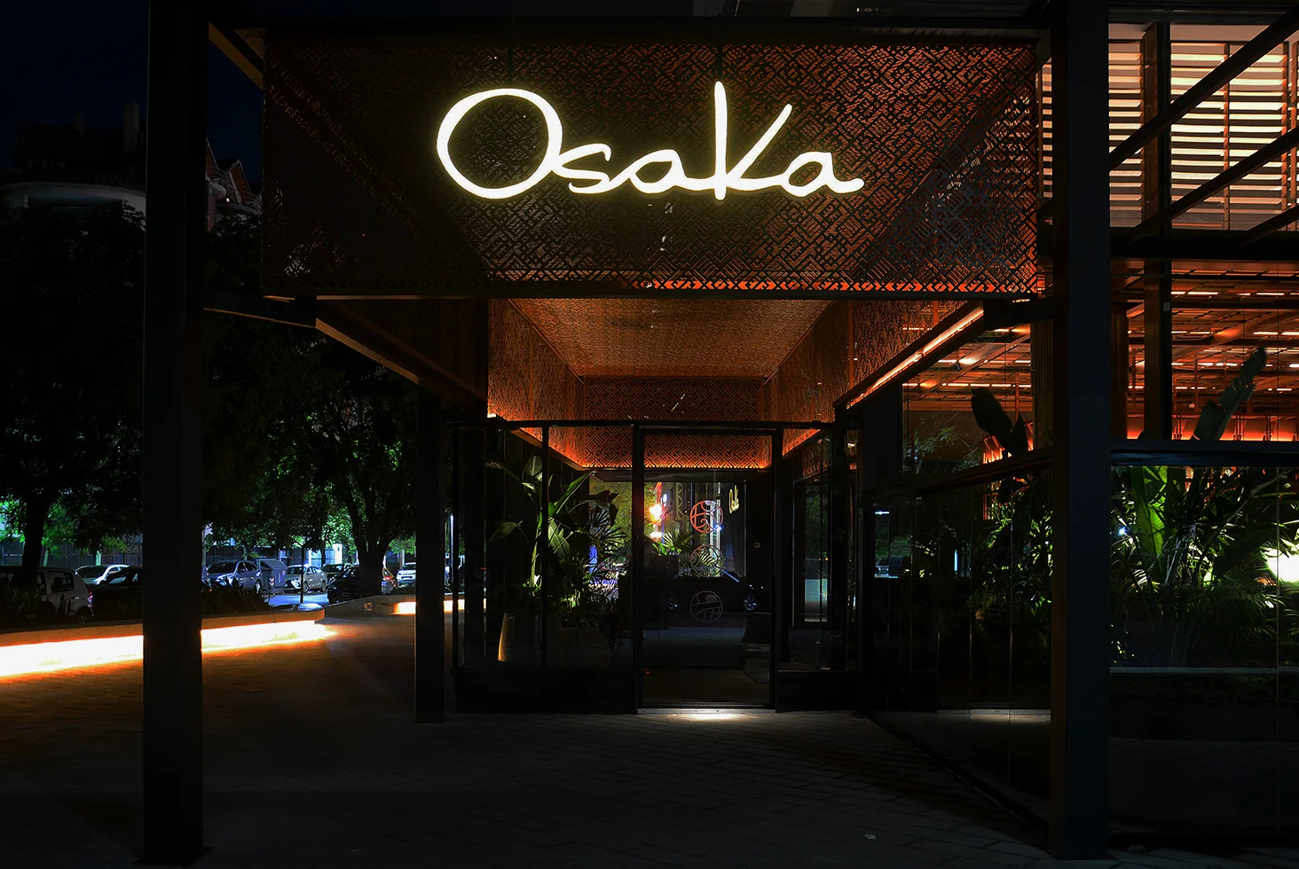 Exterior entrance with illuminated sign of Osaka Sushi Rest at night.